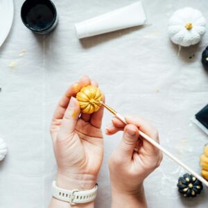 Female hands with painting pumpkins. Creative pumpkin painting ideas for Halloween and Thanksgiving